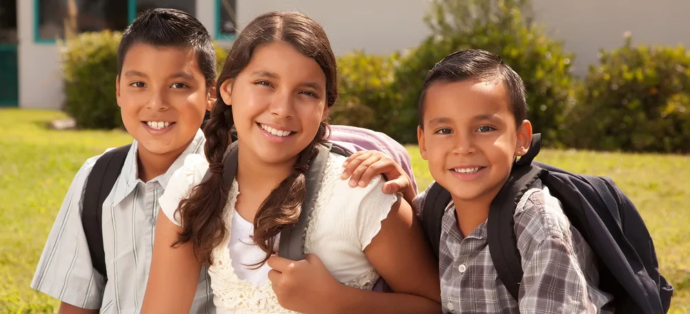Three smiling children with backpacks
