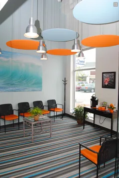 The bright Coastal Orthodontics waiting room with orange chairs and an ocean wave mural